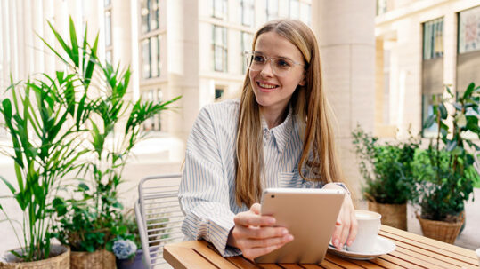 Chica joven estudiando online en una tablet, rodeada de plantas