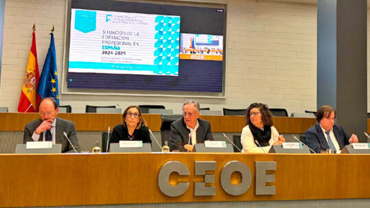 Varios ponentes en la presidencia de un auditorio con la bandera de españa y la unión europea con el logo de CEOE en el centro